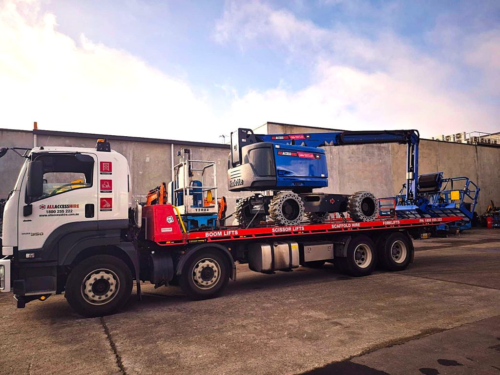 A delivery truck from All Access Hire loaded with boom lifts, ready for dispatch in Brisbane and Gold Coast for construction projects