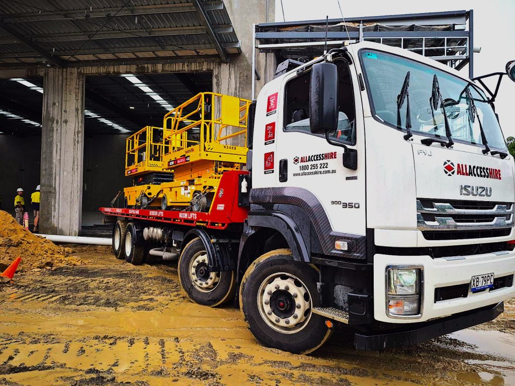 All Access Hire truck delivering yellow scissor lifts to a construction site in Brisbane, showcasing reliable equipment delivery services